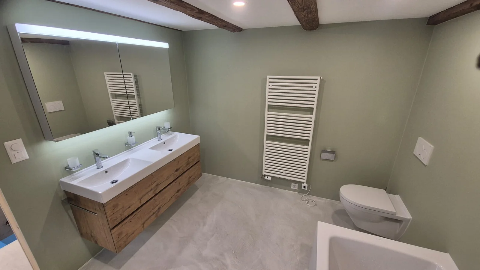 Badezimmer mit grün gestrichenen Wänden, Doppelwaschtisch und Holzunterschrank