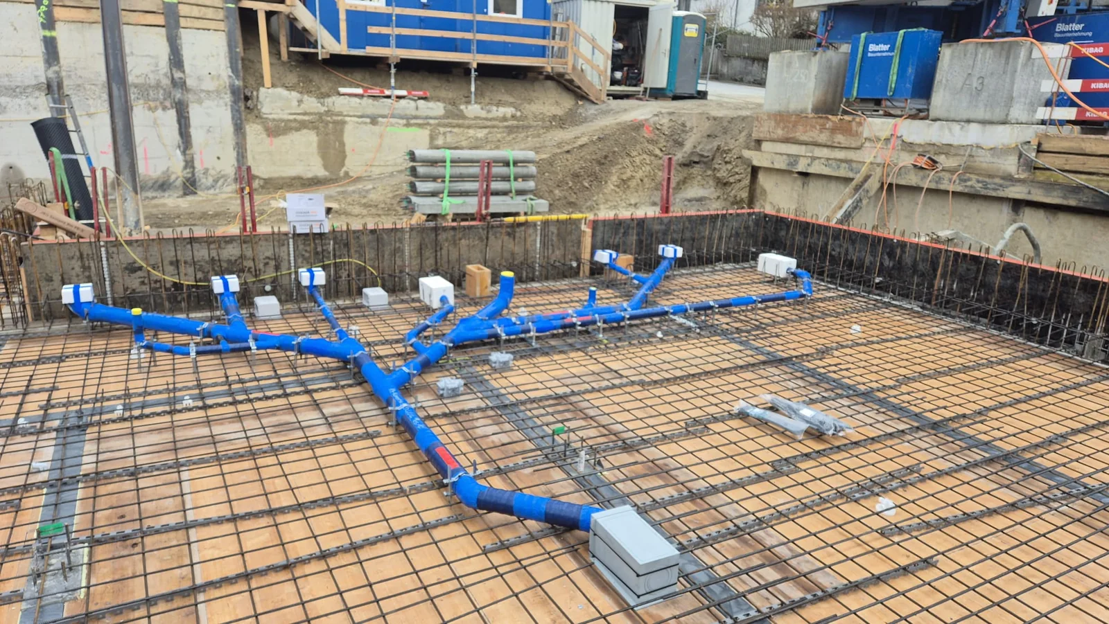Blaue Sanitärleitungen auf der Bewehrung einer Bodenplatte im Neubau